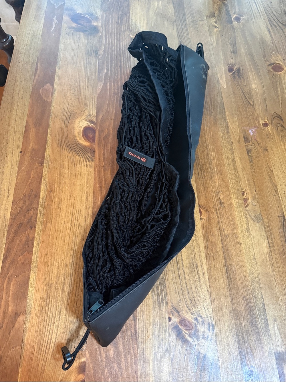 Toyota automotive cargo net resting inside its zippered black storage pouch.